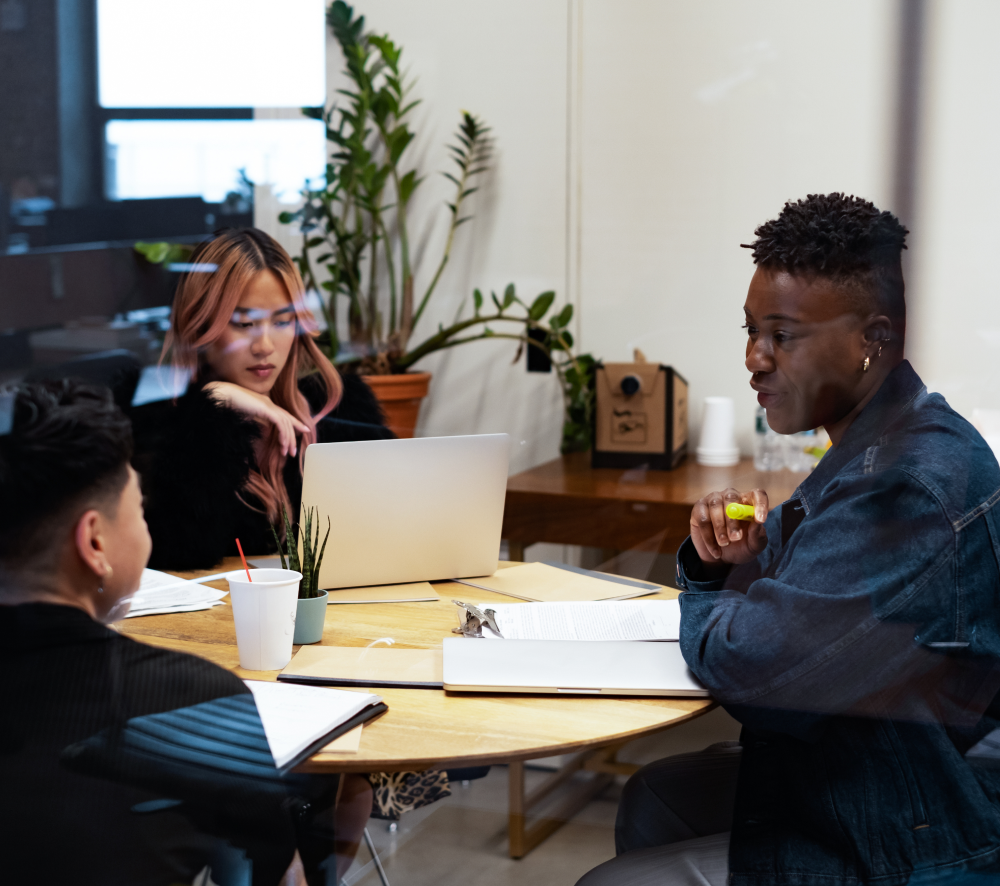 three individuals sit around a round table working with paperwork