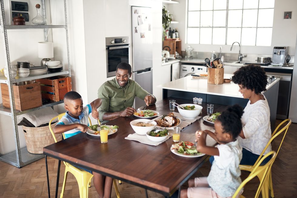 A family with two parents and two kids eating a meal at their kitchen table