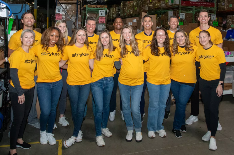 A group of Stryker employees all wearing yellow shirts with the Stryker logo on them.