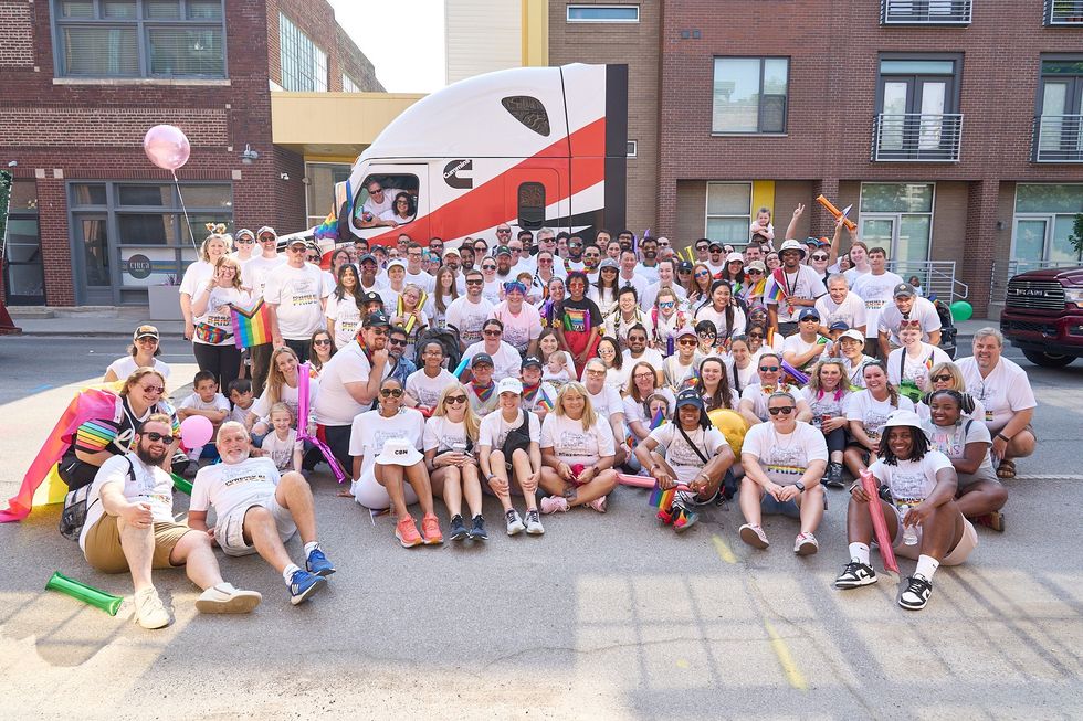 A large group of Cummins employees celebrating Pride and posing for a photo on the street