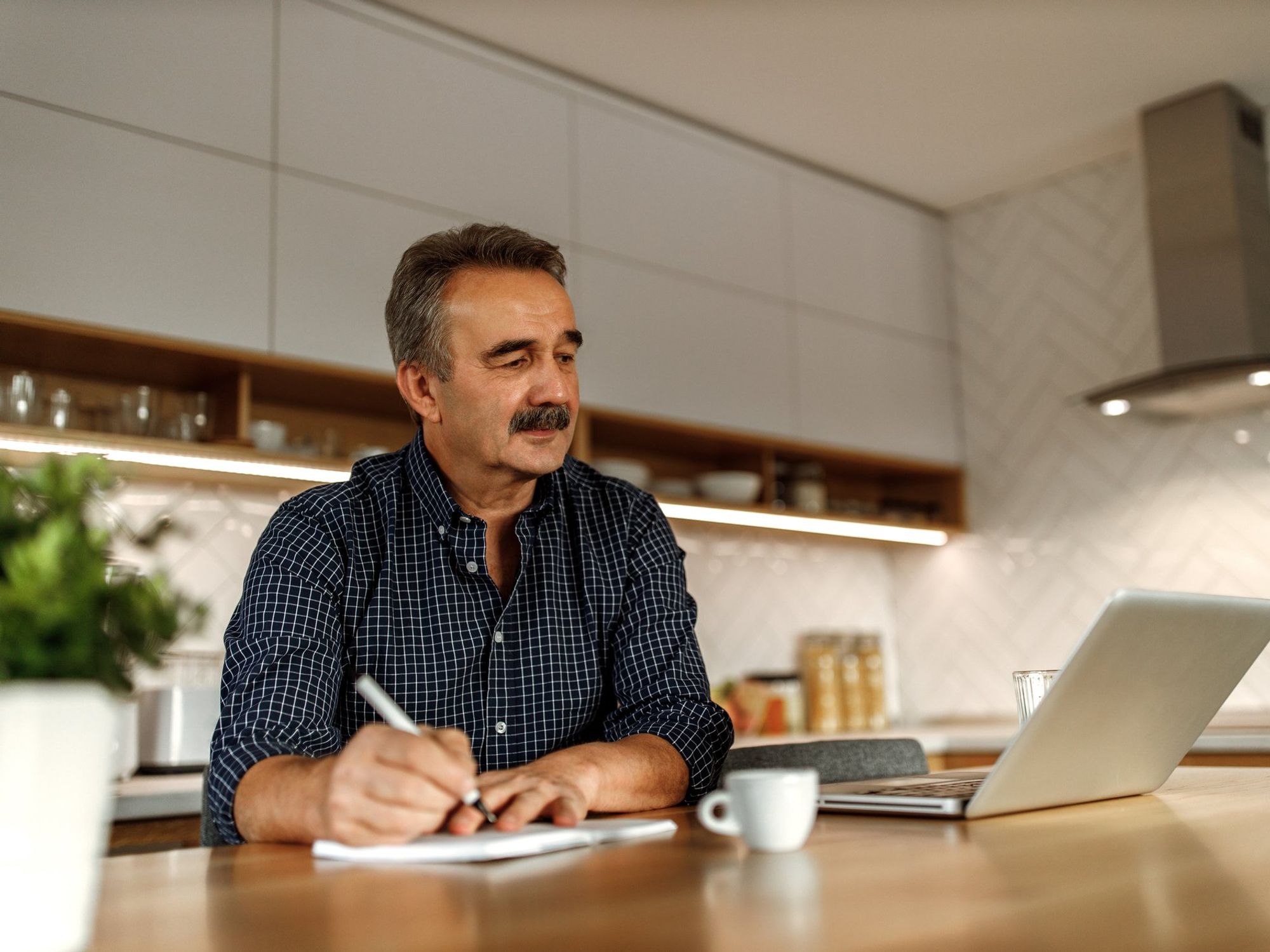 A man writing and working remotely from home on a laptop