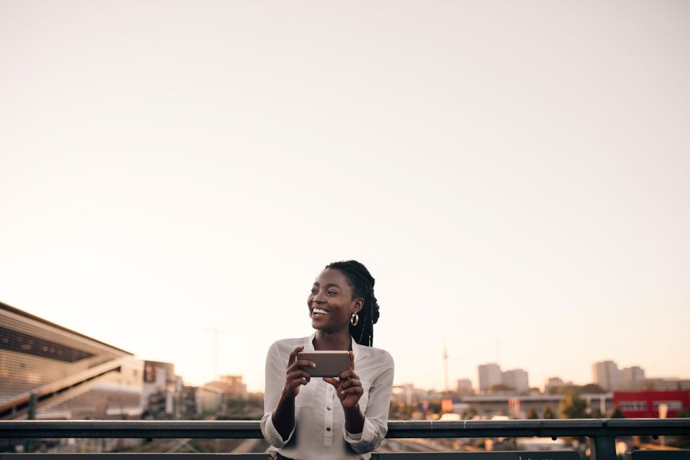 A woman on her phone smiling, standing outside of an office