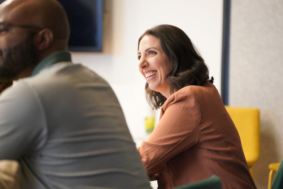 A woman smiling during a meeting in the Zillow office.