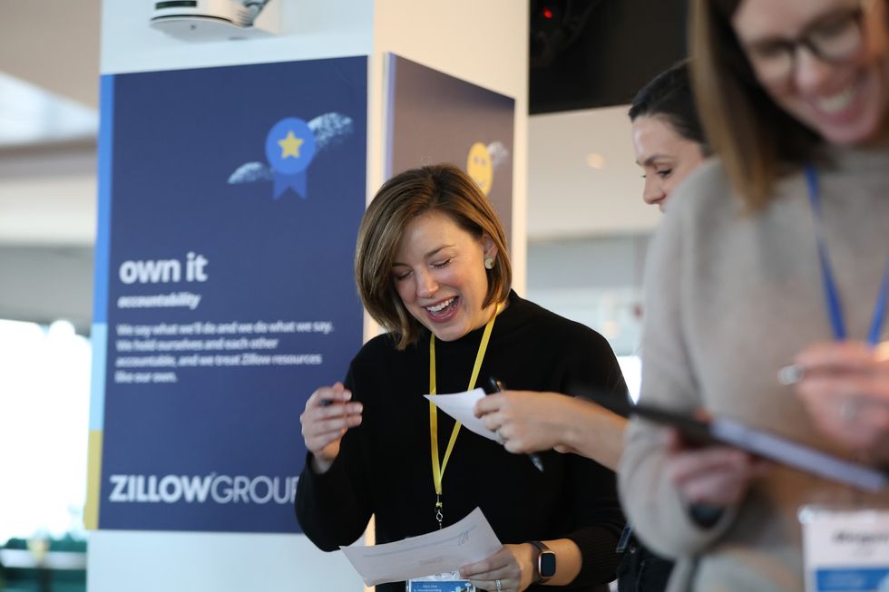 A Zillow employee smiling as she speaks with a colleague at a Zillow Group event.