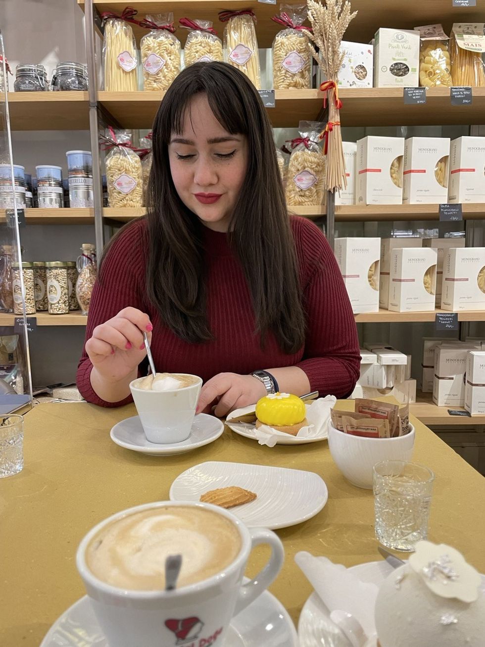 Alessia G., a 3D environment artist on the Beat Games team, stirring a coffee at a cafe.