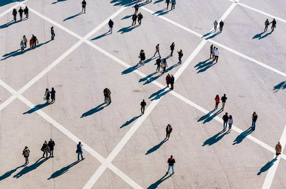 An aerial photo of multiple people walking on a concrete surface with white grid lines