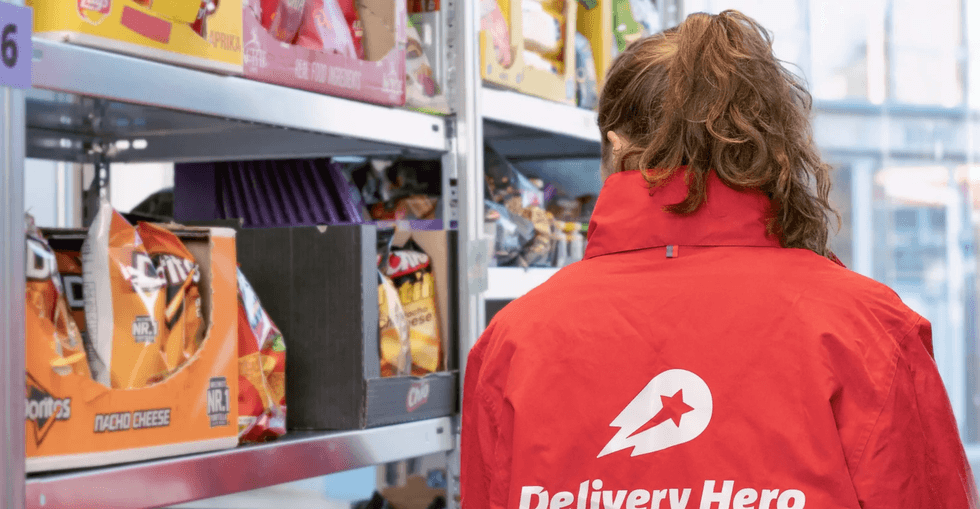 Delivery Hero employee next to a shelf of food products.