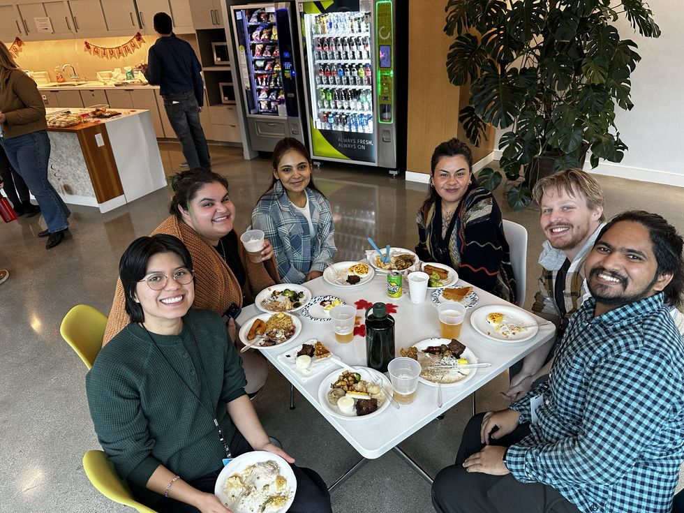 Five Esri employees eating food and smiling around a table