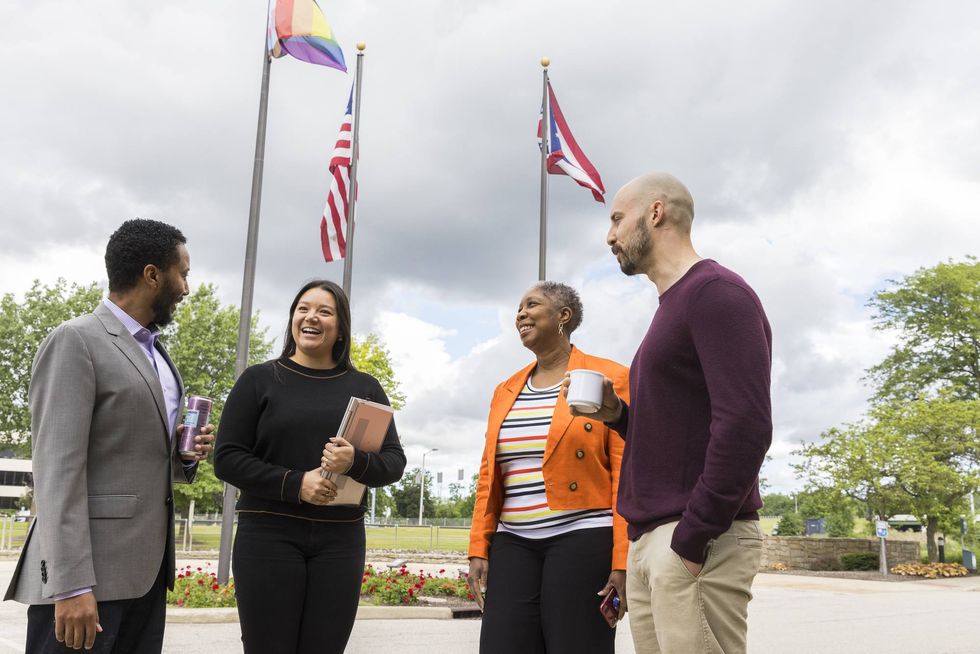 Four Nestl\u00e9 USA employees chat outdoors near U.S., Puerto Rican, and Pride flags.
