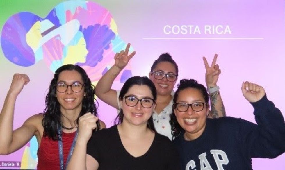 Four women with their arms up in front of a background that says 'Costa Rica'