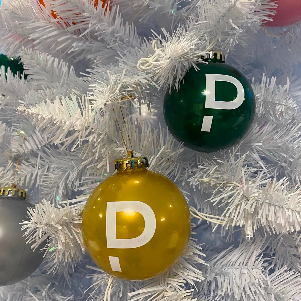 green and yellow pagerduty ball ornaments on a white artificial tree