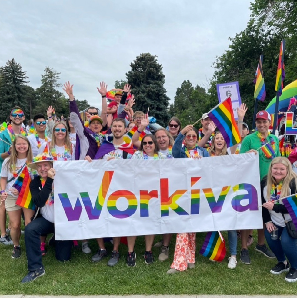 Group of people celebrating Pride and holding a rainbow Workiva banner