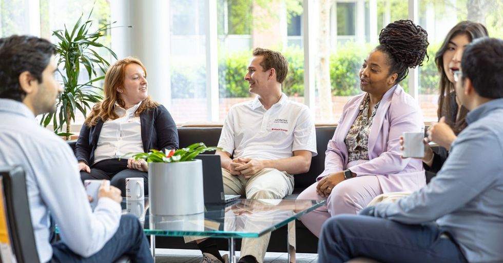 Hitachi Energy employees chatting in a circle and sitting on couches in an office