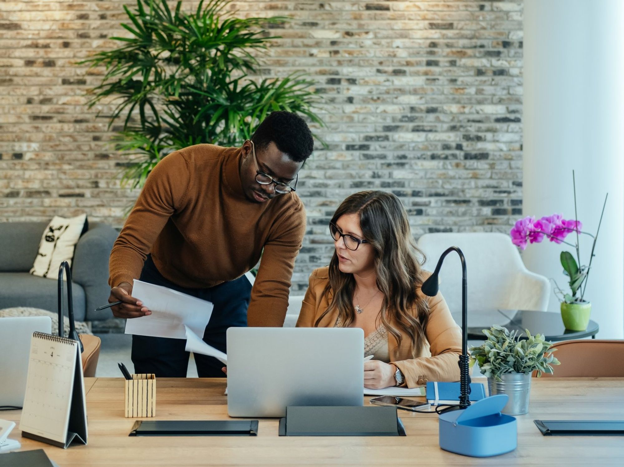 Man and woman looking at papers working on a laptop