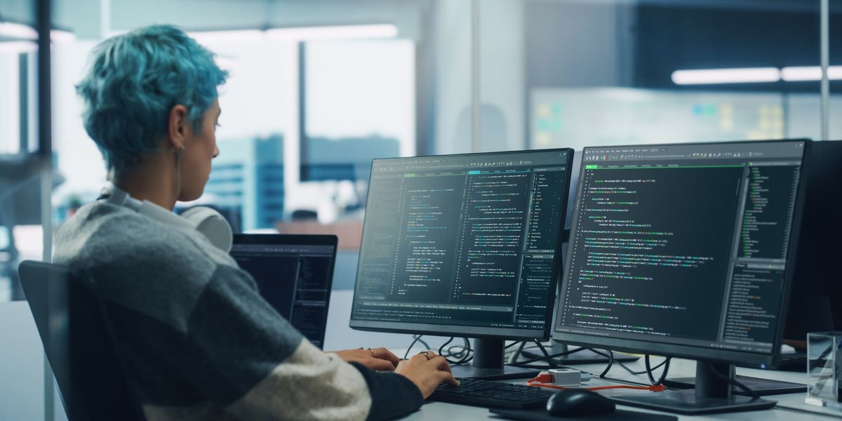 Person with short blue hair using artificial intelligence to code