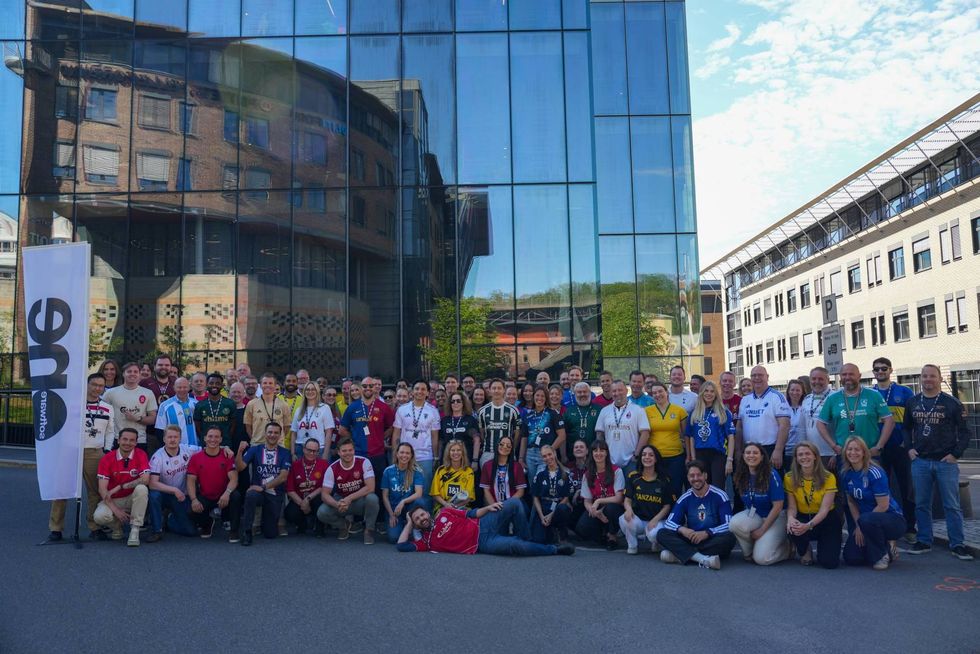SoftwareOne employees gather outside an office wearing soccer jerseys for a company event.