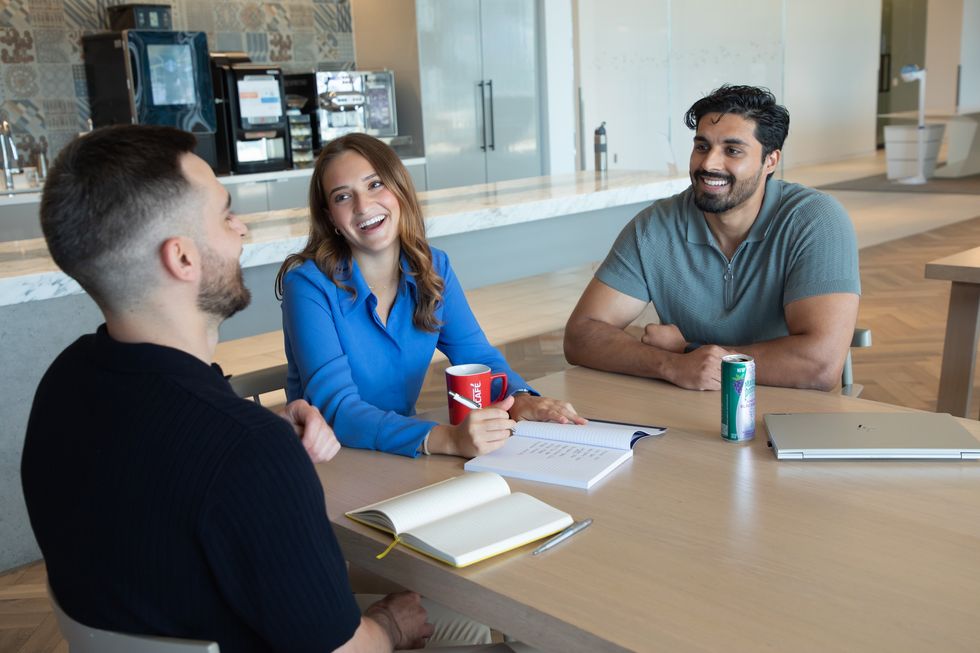 Three Nestle employees smiling and chatting at a table in a Nestle office