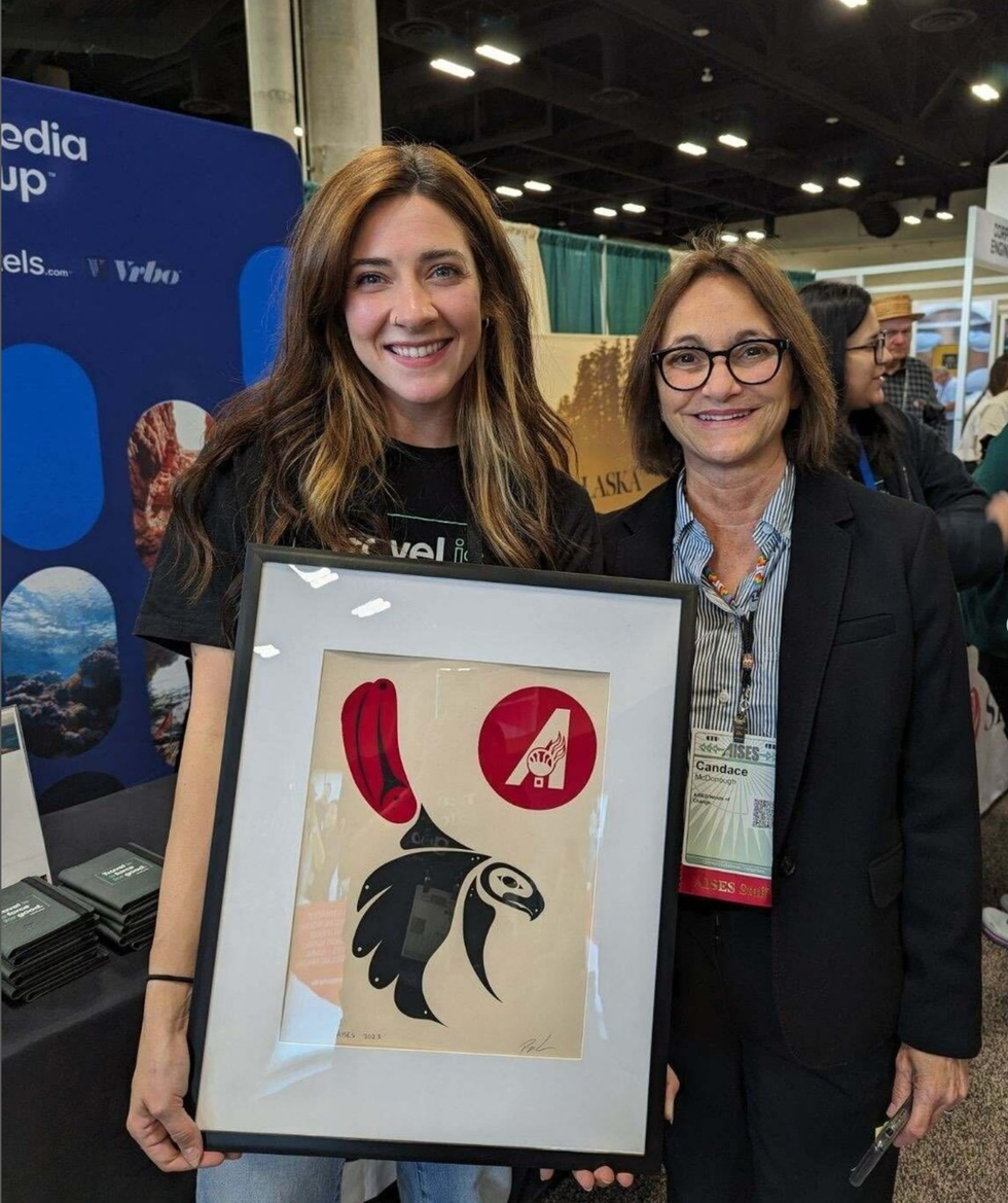 Two Expedia Group team members smiling and holding an image of a Native American design