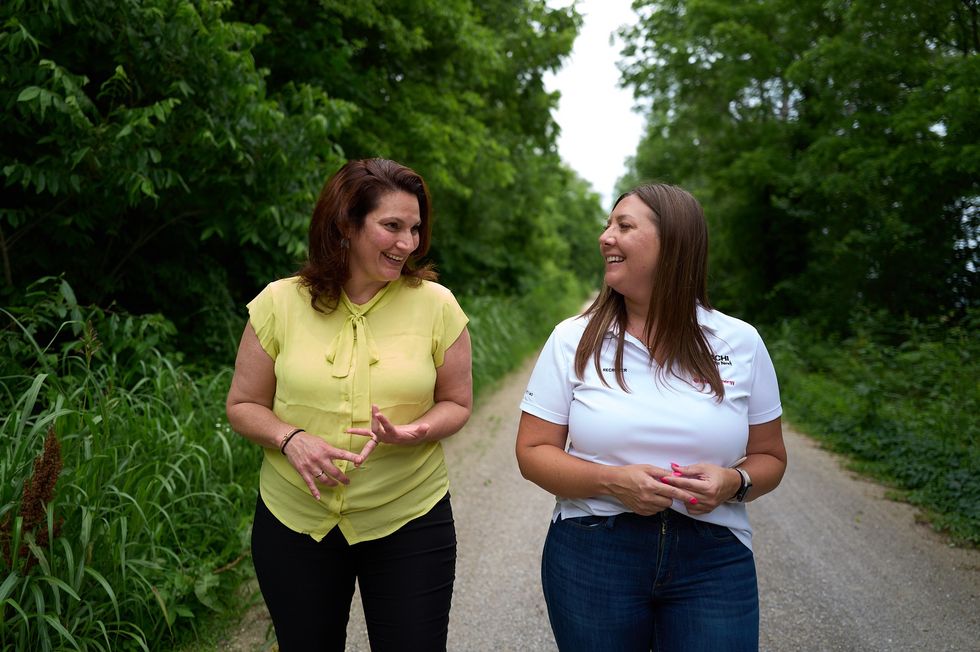 Two Hitachi employees smiling and walking on an outdoor path
