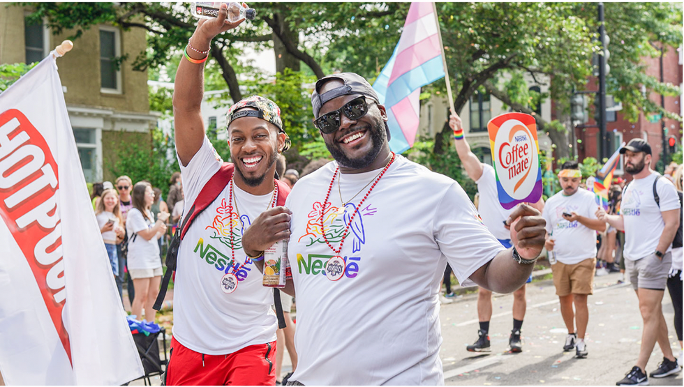 Two men wearing rainbow Nestl\u00e9 shirts attend a Pride march