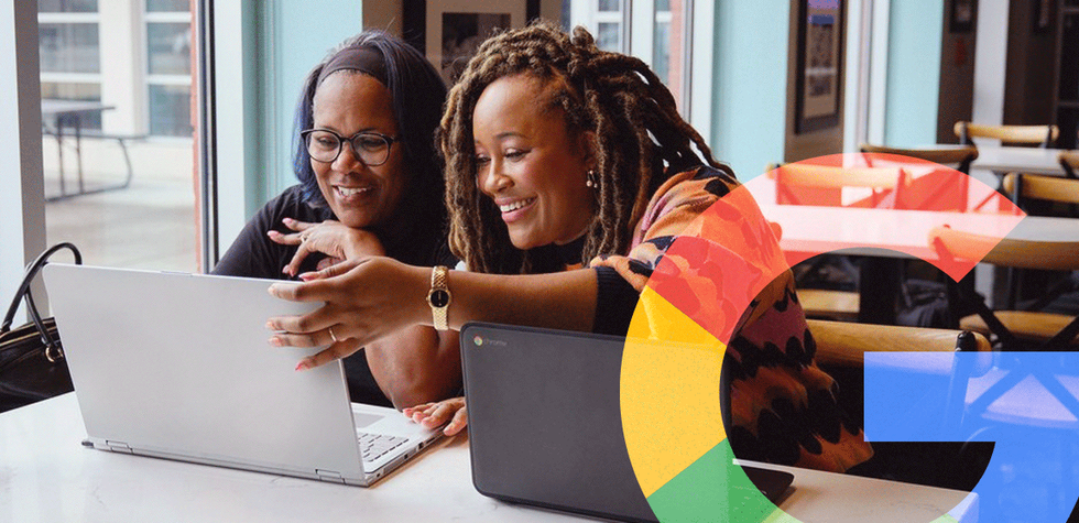Two women looking at a computer, smiling, as one teaches the other. Embossed "G" for Google on the righthand side.