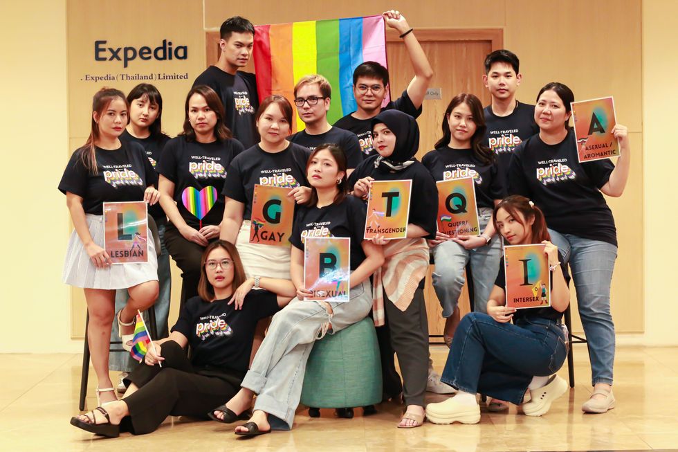 Various Expedia Group employees holding a Pride flag and LGBTQIA signs
