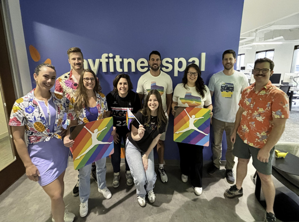 Various MyFitnessPal employees holding Pride signs inside their office
