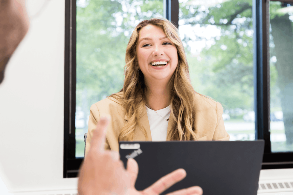 Woman smiling working on a laptop.