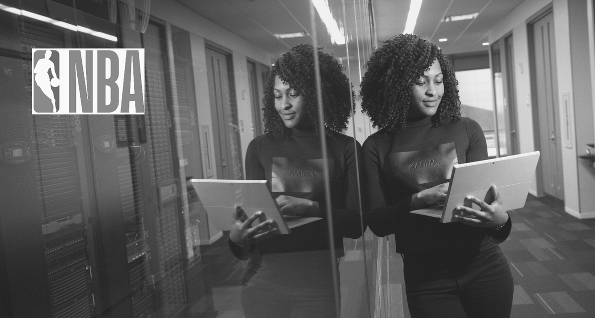 Woman with laptop next to NBA logo