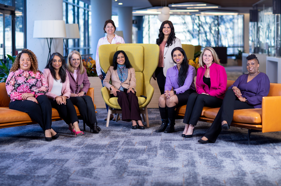 Women at Freddie Mac smiling and posing on couches and chairs in the office