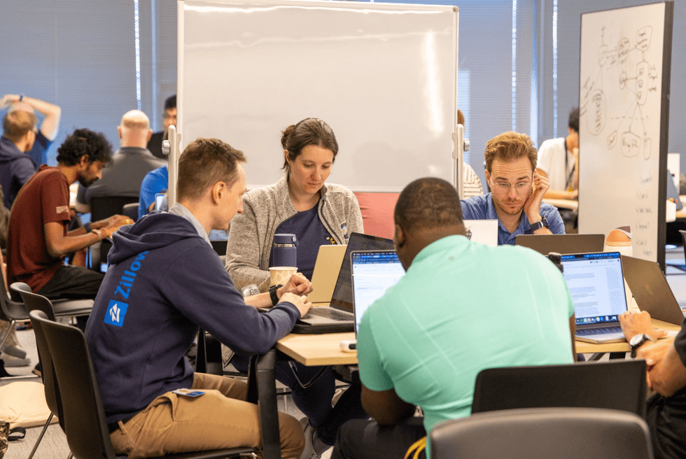 Zillow employees collaborate around laptops and whiteboards during Hack Week.